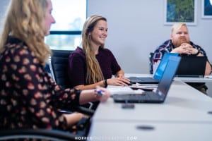 3 people sitting at a table with their laptops