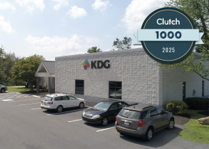 Exterior view of a white office building with the KDG logo, three parked cars, and a Clutch 1000 2025 award badge in the top right corner. Exterior view of a white office building with the KDG logo, three parked cars, and a Clutch 1000 2025 award badge in the top right corner.