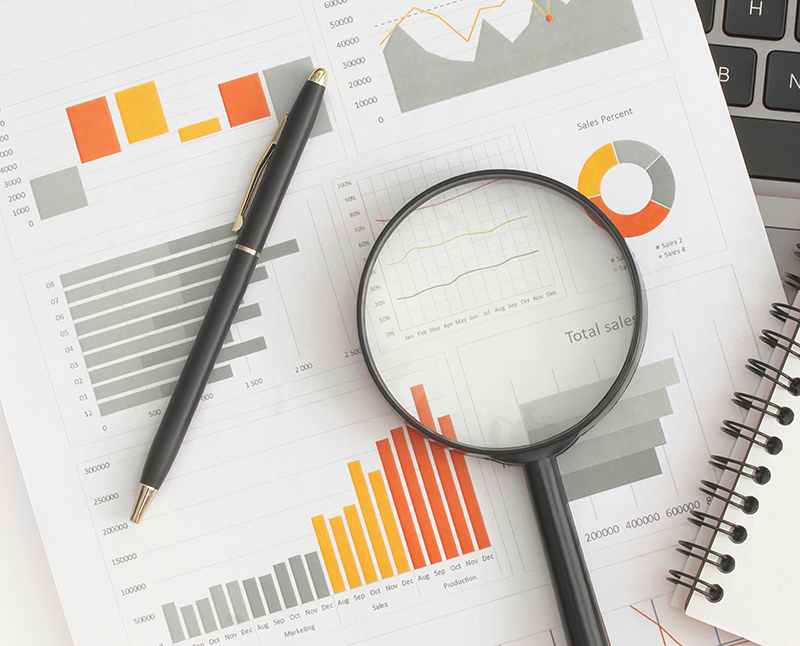 A pen, magnifying glass, and notebook on printed business charts and graphs near a laptop keyboard—tools essential for analyzing digital marketing trends. A pen, magnifying glass, and notebook on printed business charts and graphs near a laptop keyboard—tools essential for analyzing digital marketing trends.